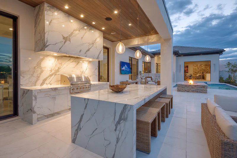 Outdoor kitchen with pool and firepit at dusk